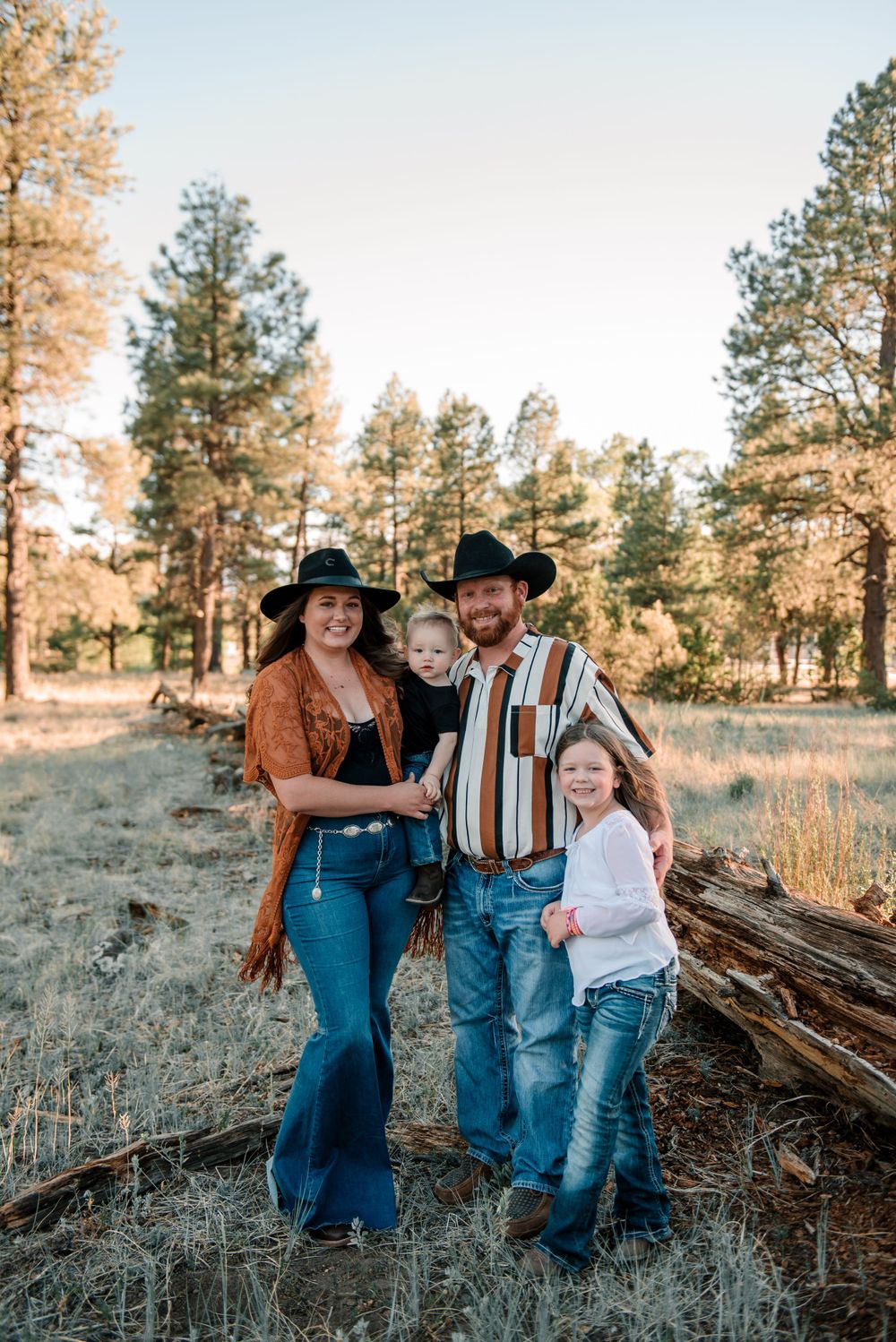 Family dressed in casual western style posing together in natural outdoor setting.