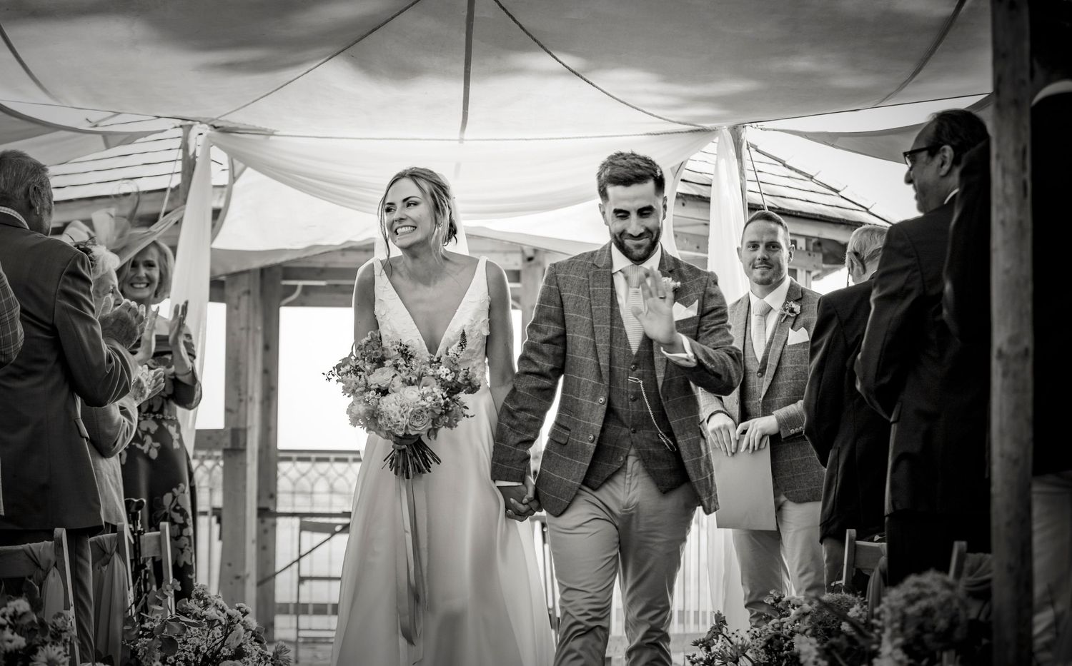 Wedding guests gathered under a large white tent for an outdoor celebration.