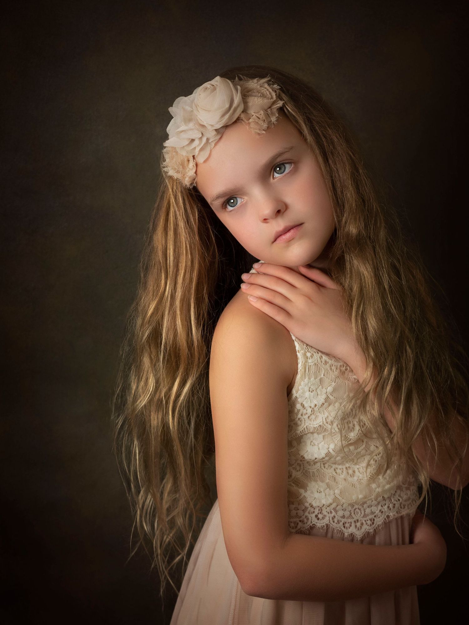 portrait of young girl with long hair holding her hand on her sholder looking to the side