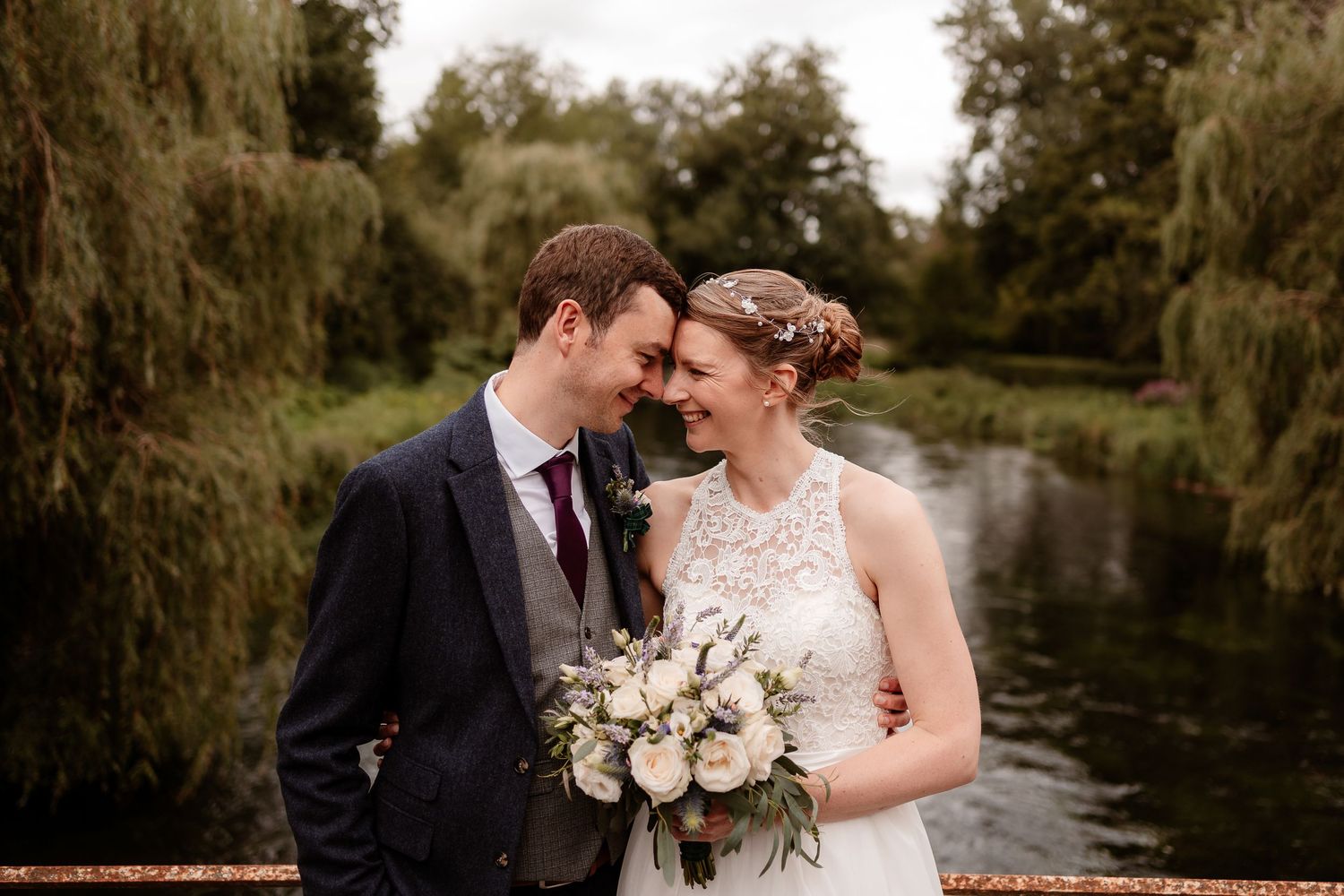 A bride and groom rest their foreheads together in front of a river scene at their Kimbridge Barn wedding day.