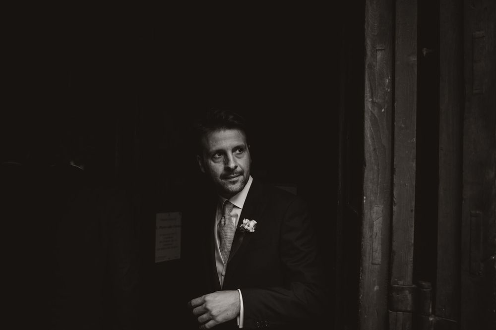 Dramatic black and white portrait captures intimate wedding moment in dark setting.