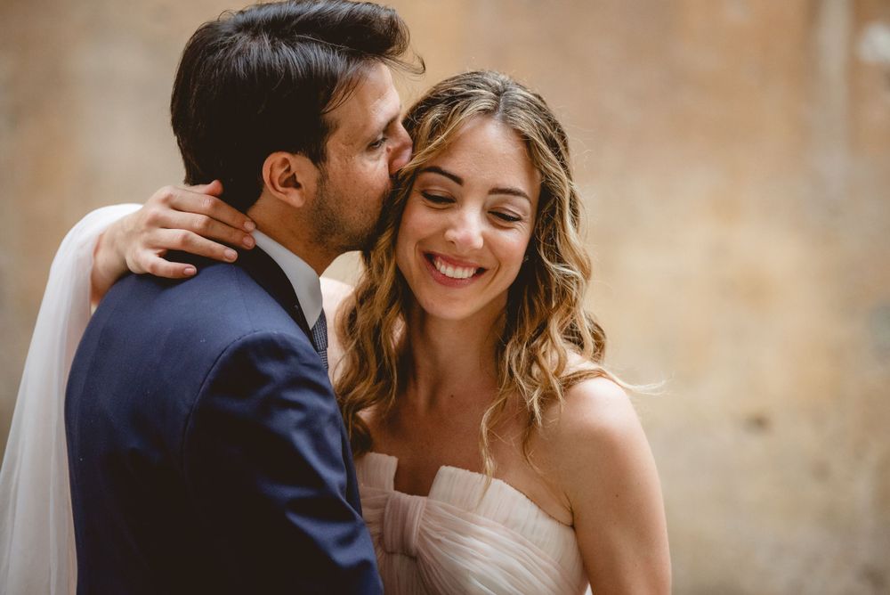 Romantic wedding portraits against a warm stone wall background.