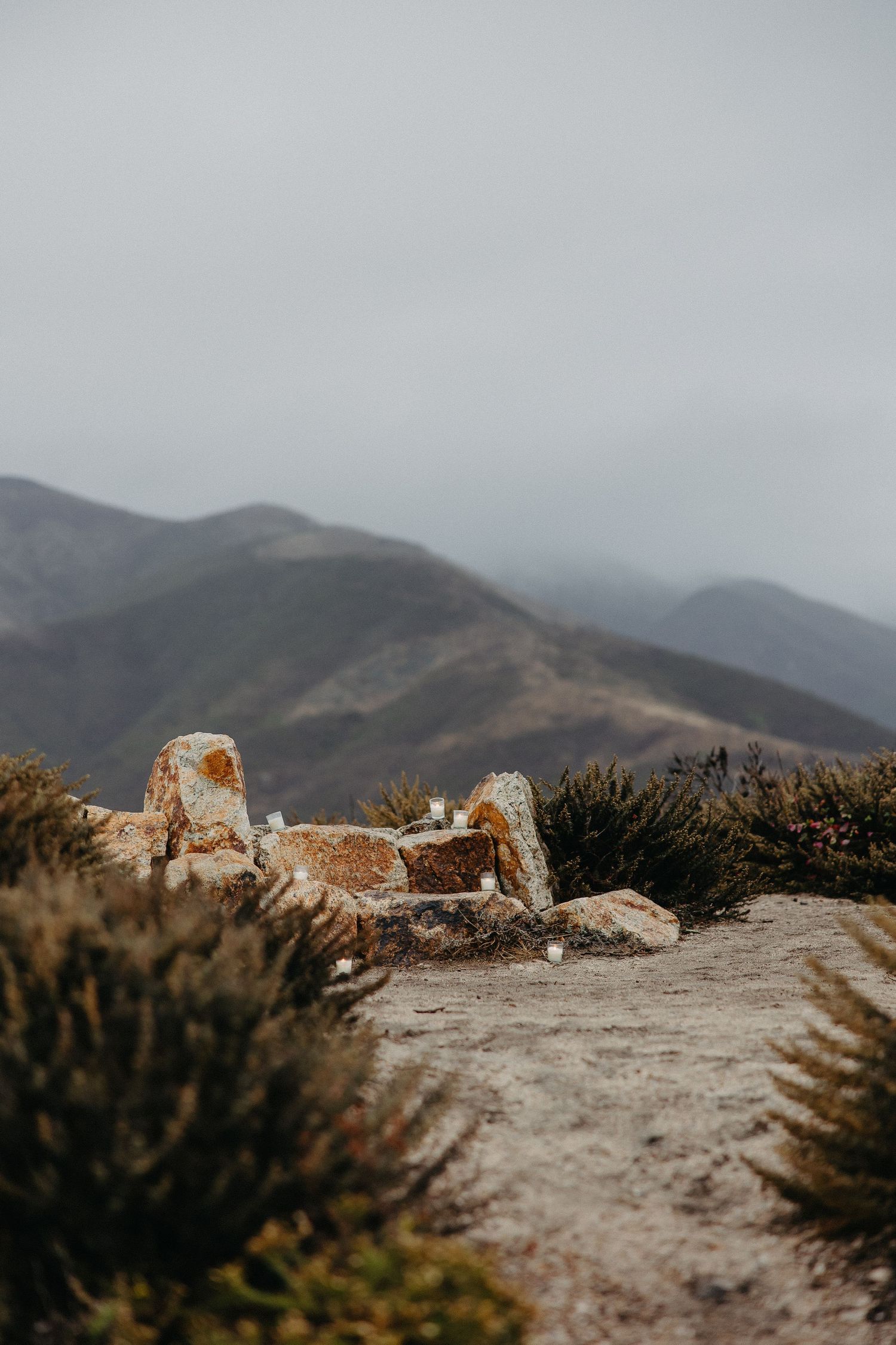 A rocky coastal viewpoint with weathered concrete posts against misty mountain backdrop.