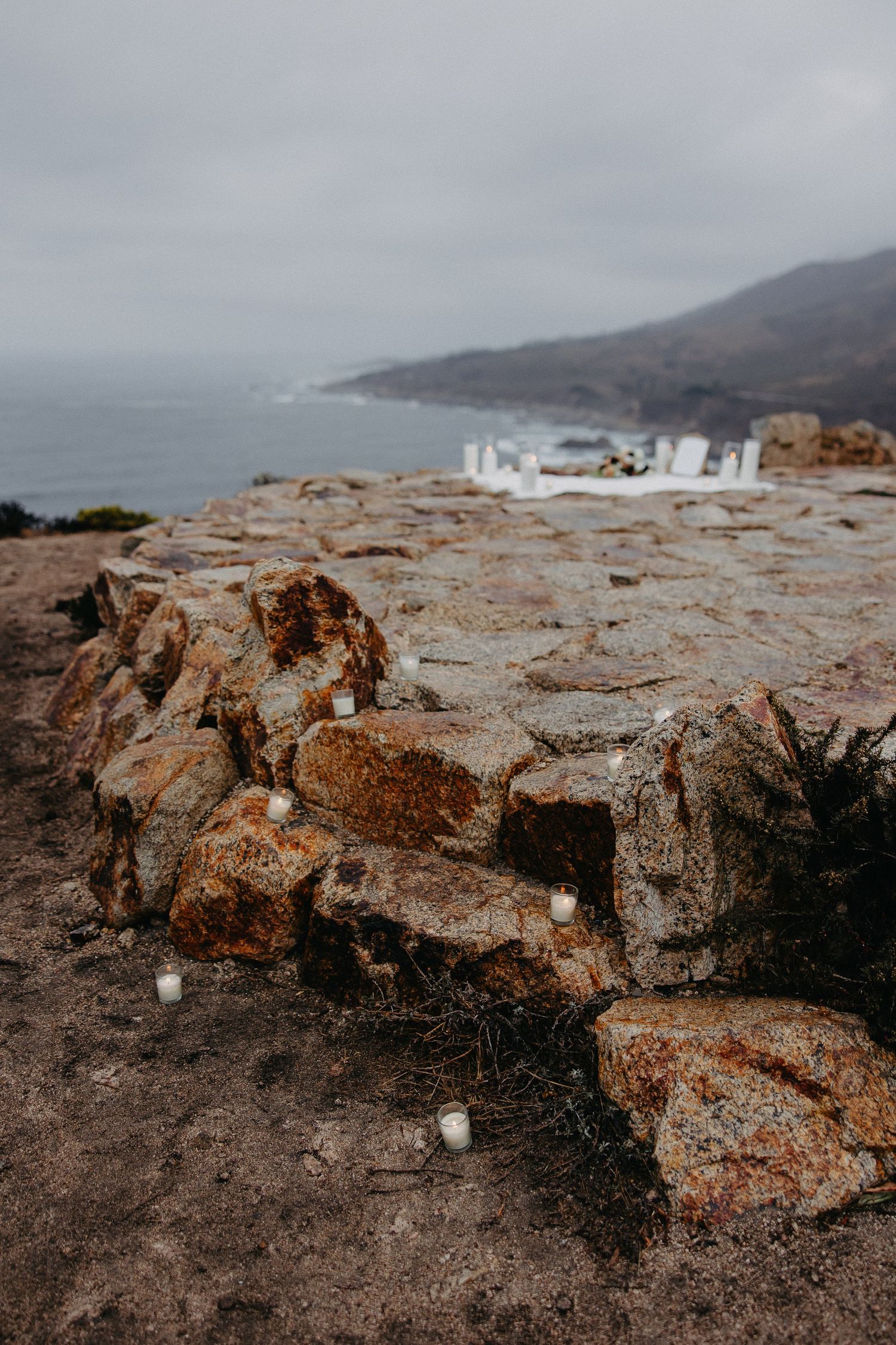 Rocky coastal cliff edge with white decor visible in the misty background.