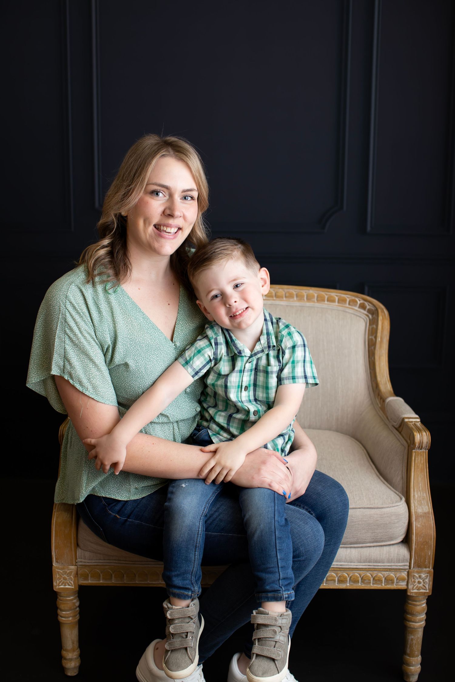 Casual portrait of parent and child sitting together on vintage beige armchair.