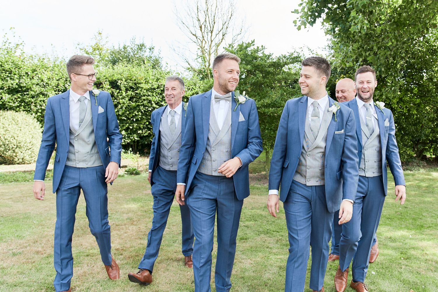 Groom and groomsmen walking to wedding venue at Godwick Hall in Norfolk, by Norfolk wedding photographer Faye Amare