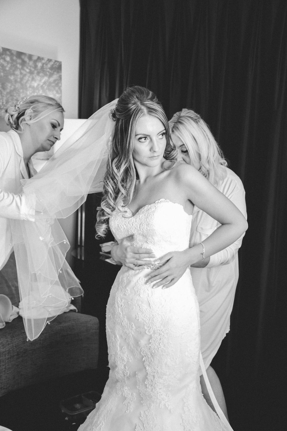 Wedding preparations showing a bride in a fitted lace gown with flowing veil.