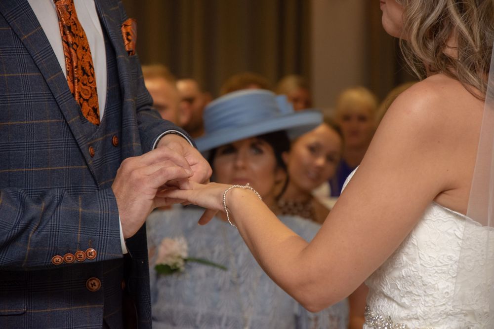 Close-up of hands during ring exchange at wedding ceremony.