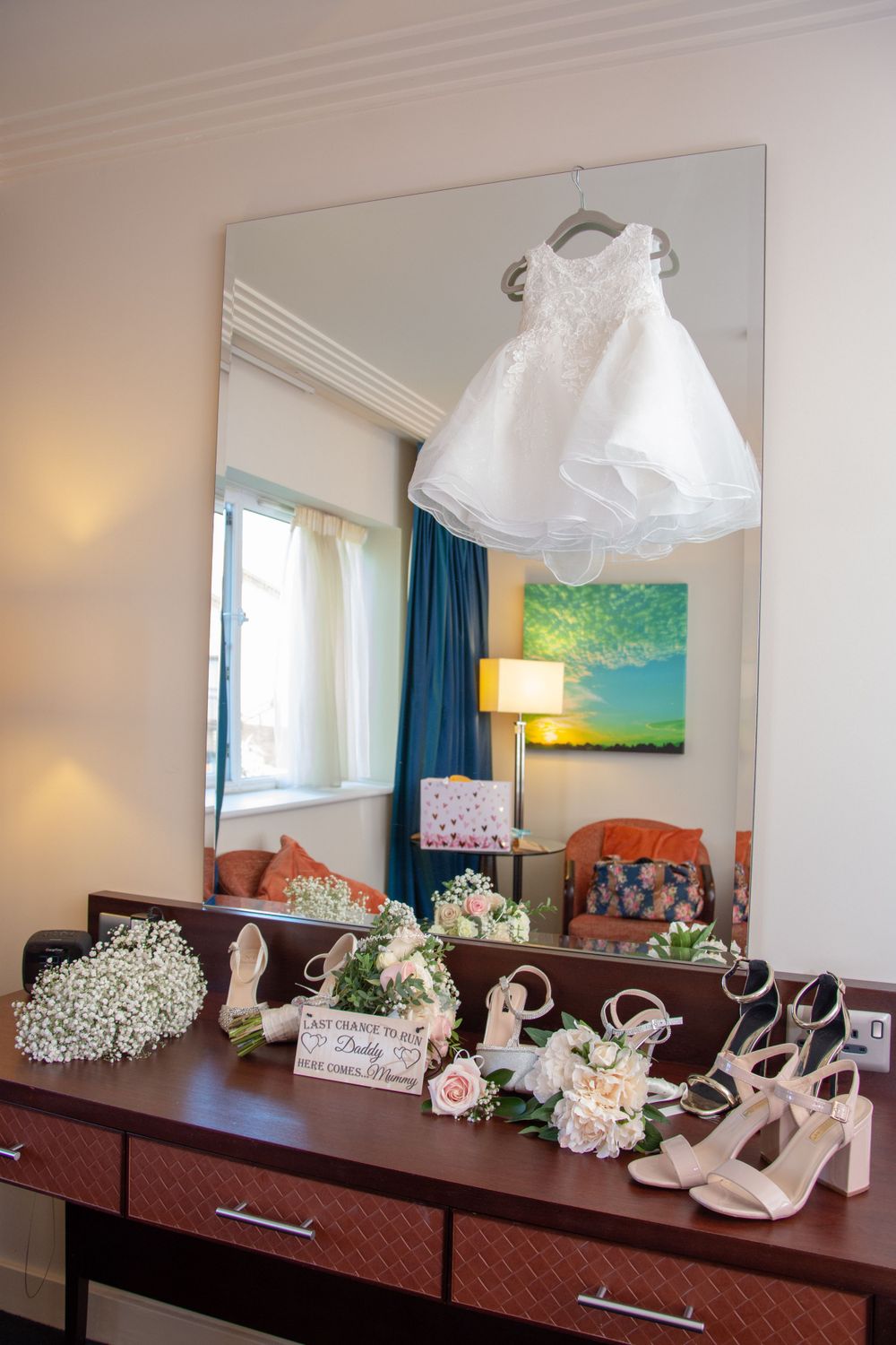 Bridal accessories and dress displayed on a dresser with mirror and decorative elements.