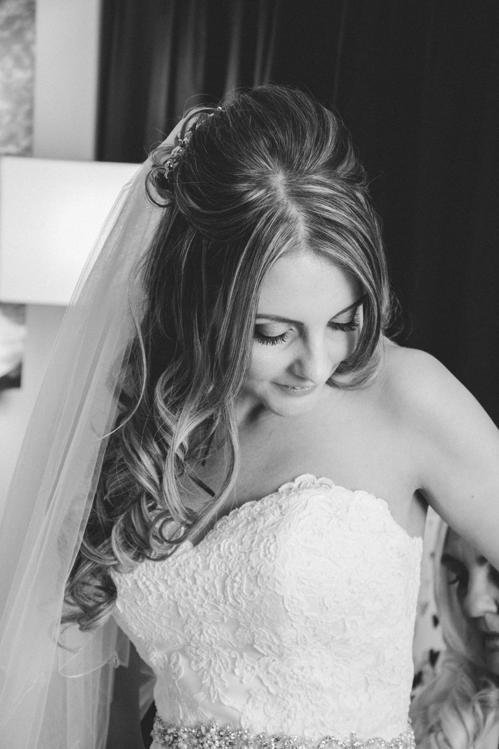 Black and white portrait of bride in strapless lace wedding gown with flowing curls.