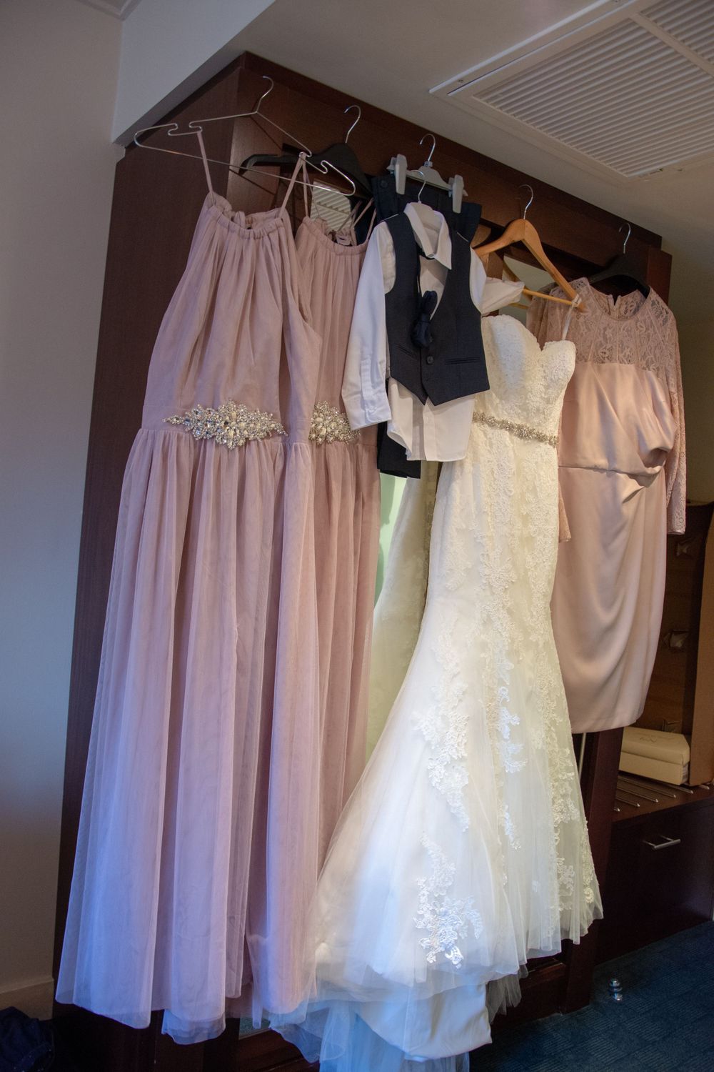 Wedding party dresses in various styles and colors hanging together on a rack.