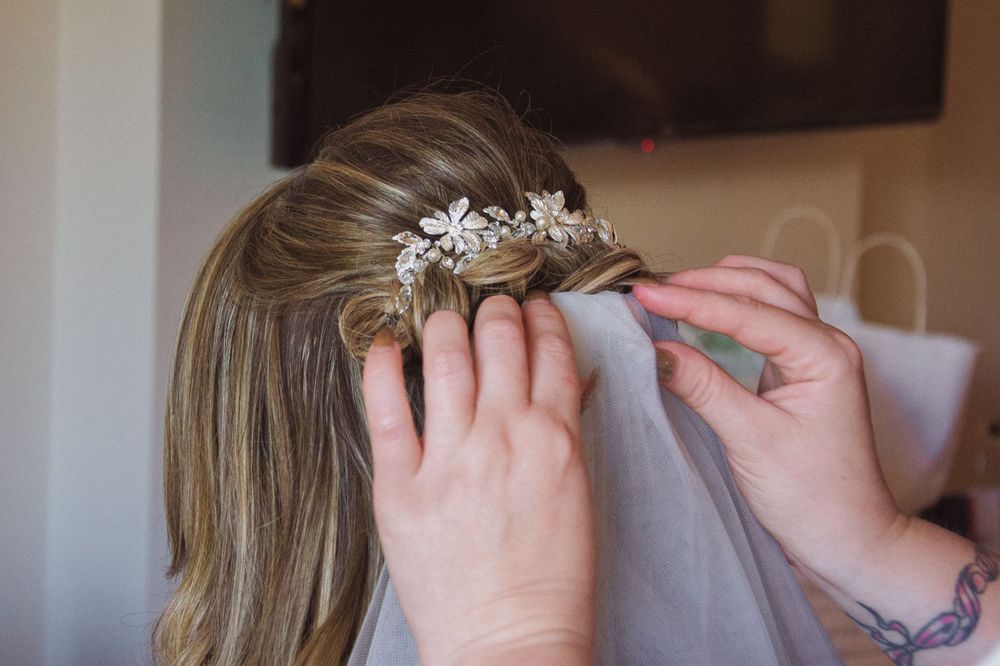 Delicate crystal hair accessory being placed in blonde hair for a wedding ceremony.