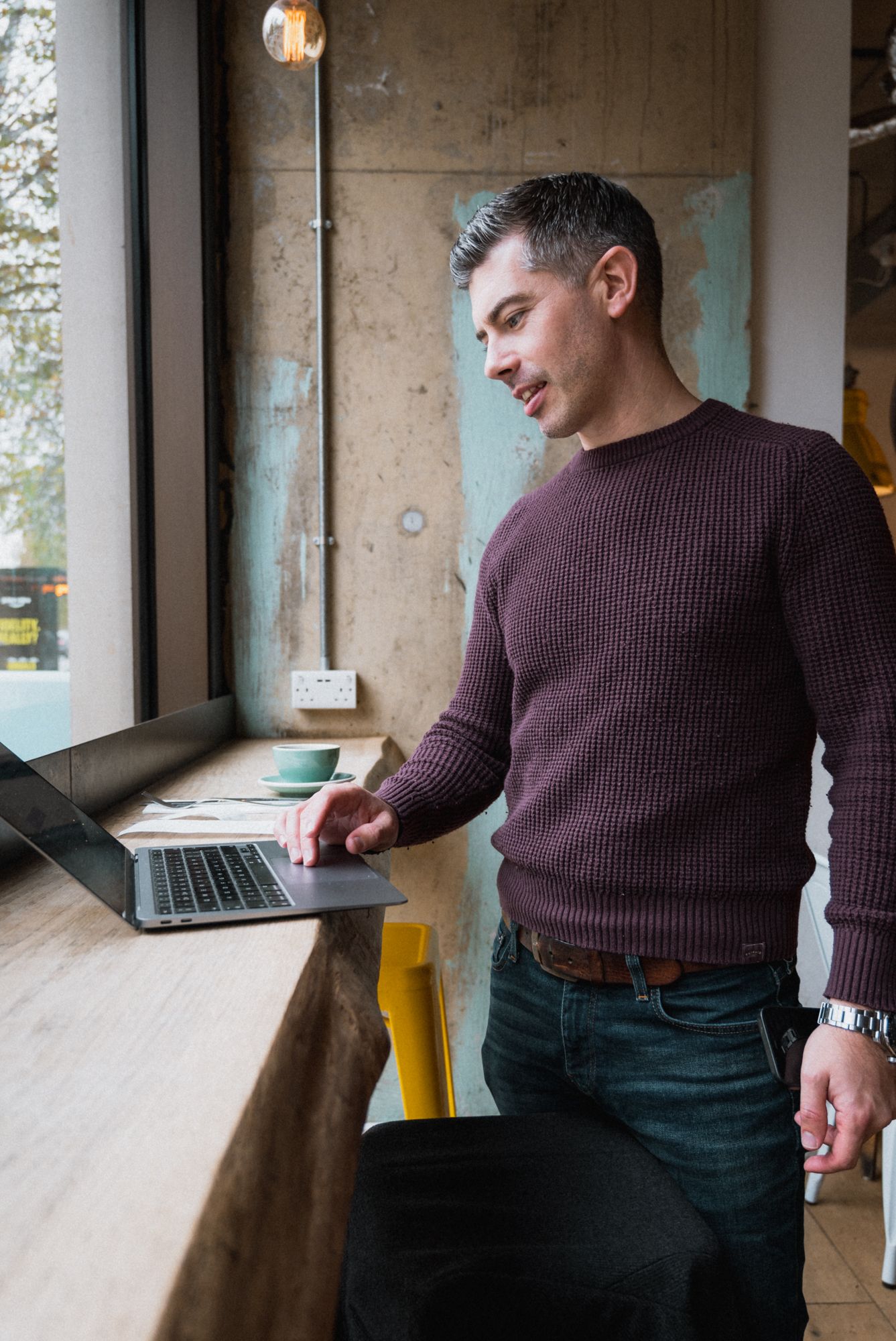 a man standing in a coffee shop working on his laptop