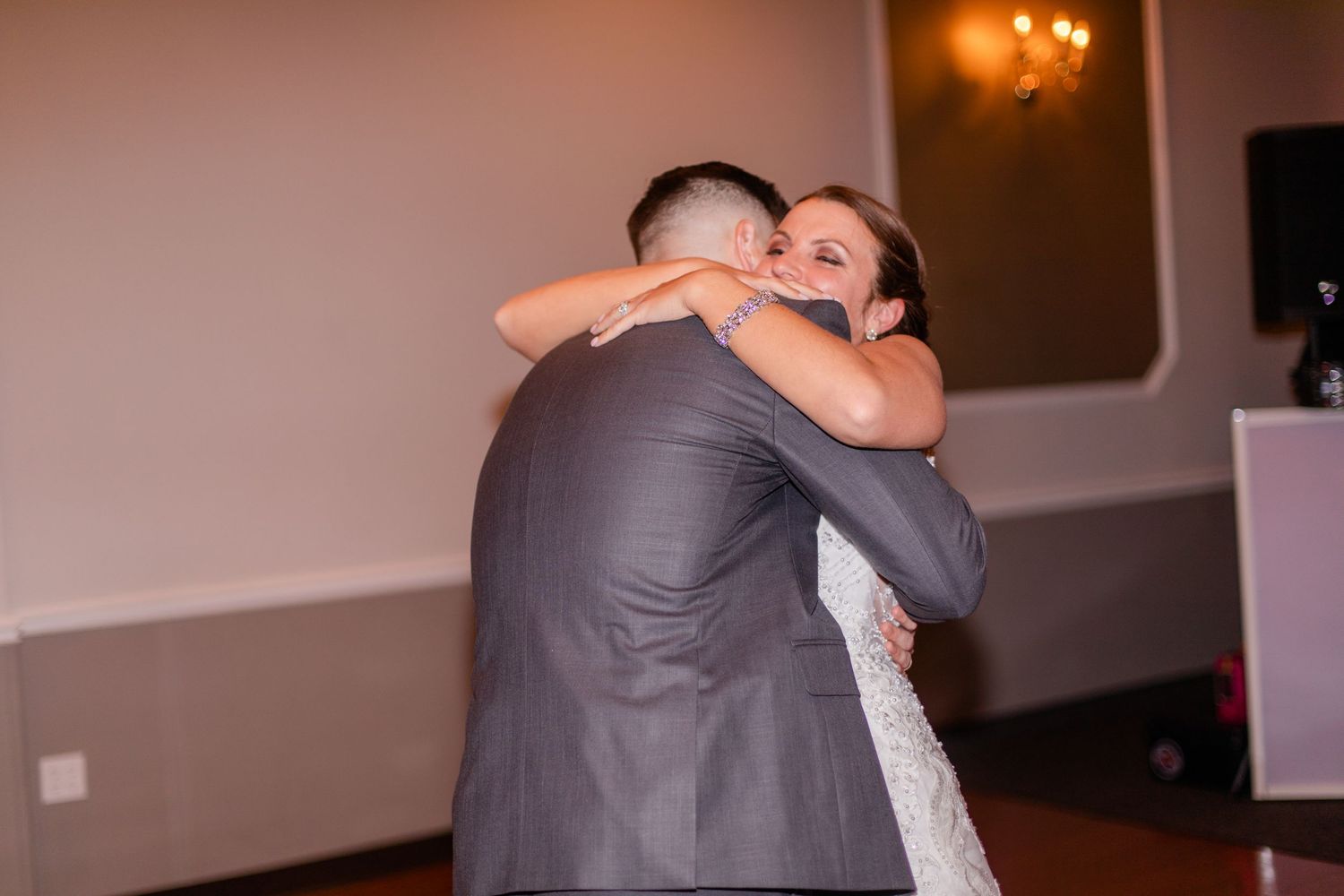 Couple dancing together in an elegant ballroom with warm lighting.