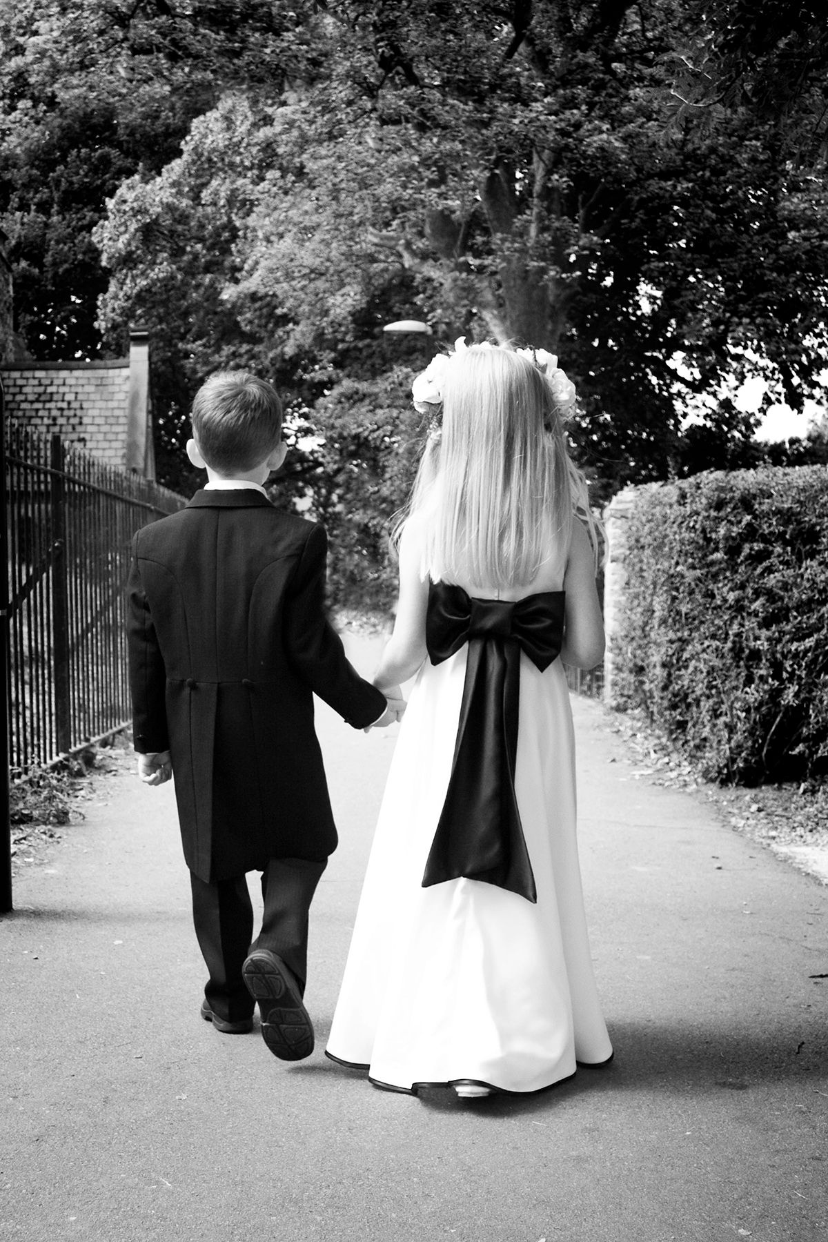 small pageboy and bridesmaid holding hands walking to church