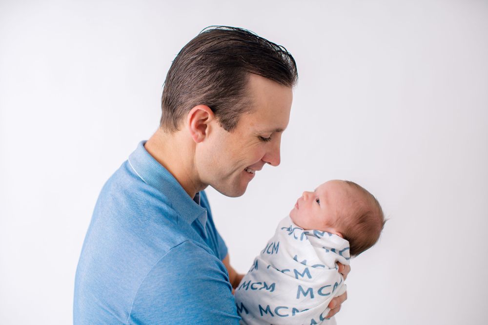 A heartwarming moment between parent and newborn baby during a professional portrait session.