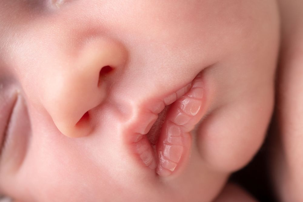 Macro photograph of sleeping baby's lips and nose showing soft peaceful features.