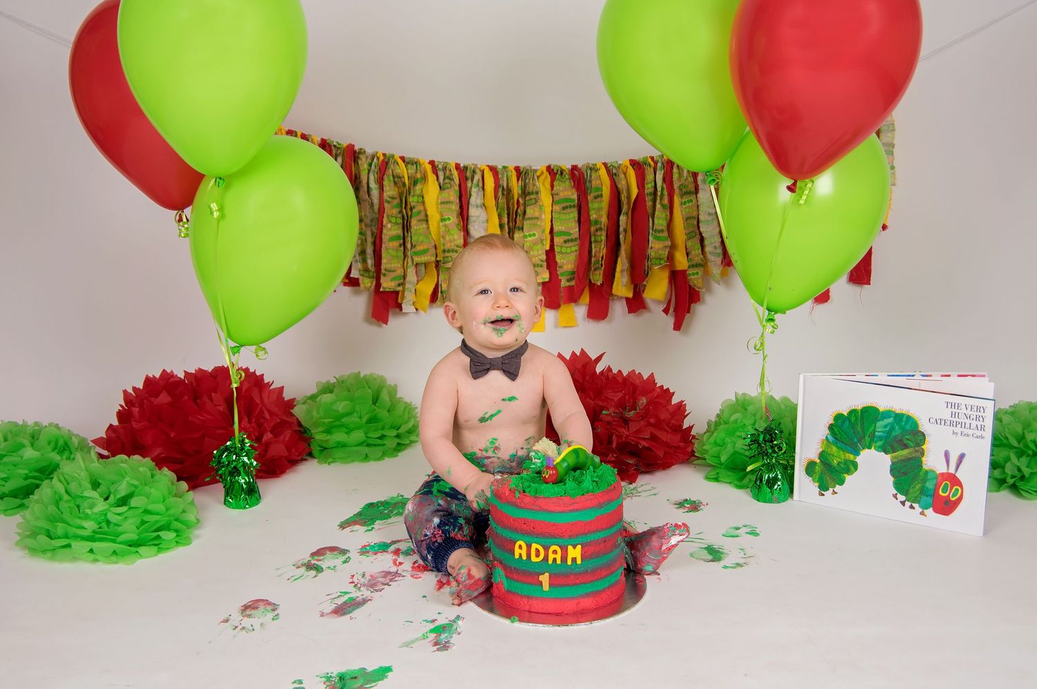 baby eating cake with red and green theme and decorations