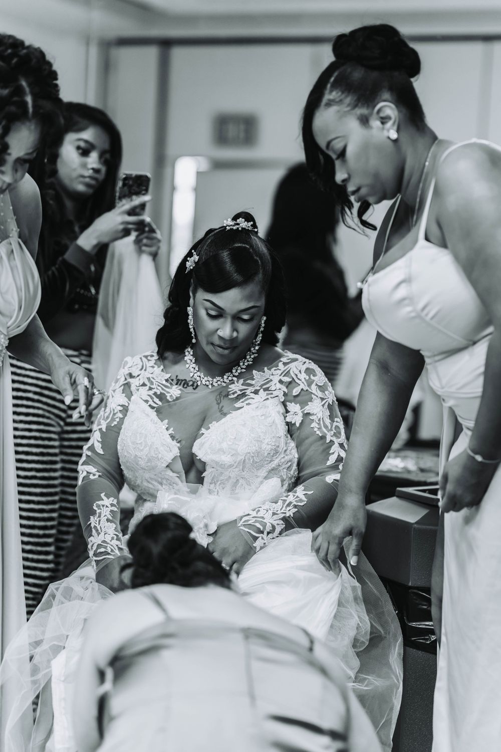 Wedding preparation scene showing attendants assisting with final touches.