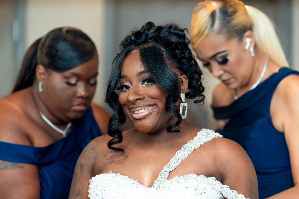 Three women in formal attire share a joyful moment during a wedding celebration.