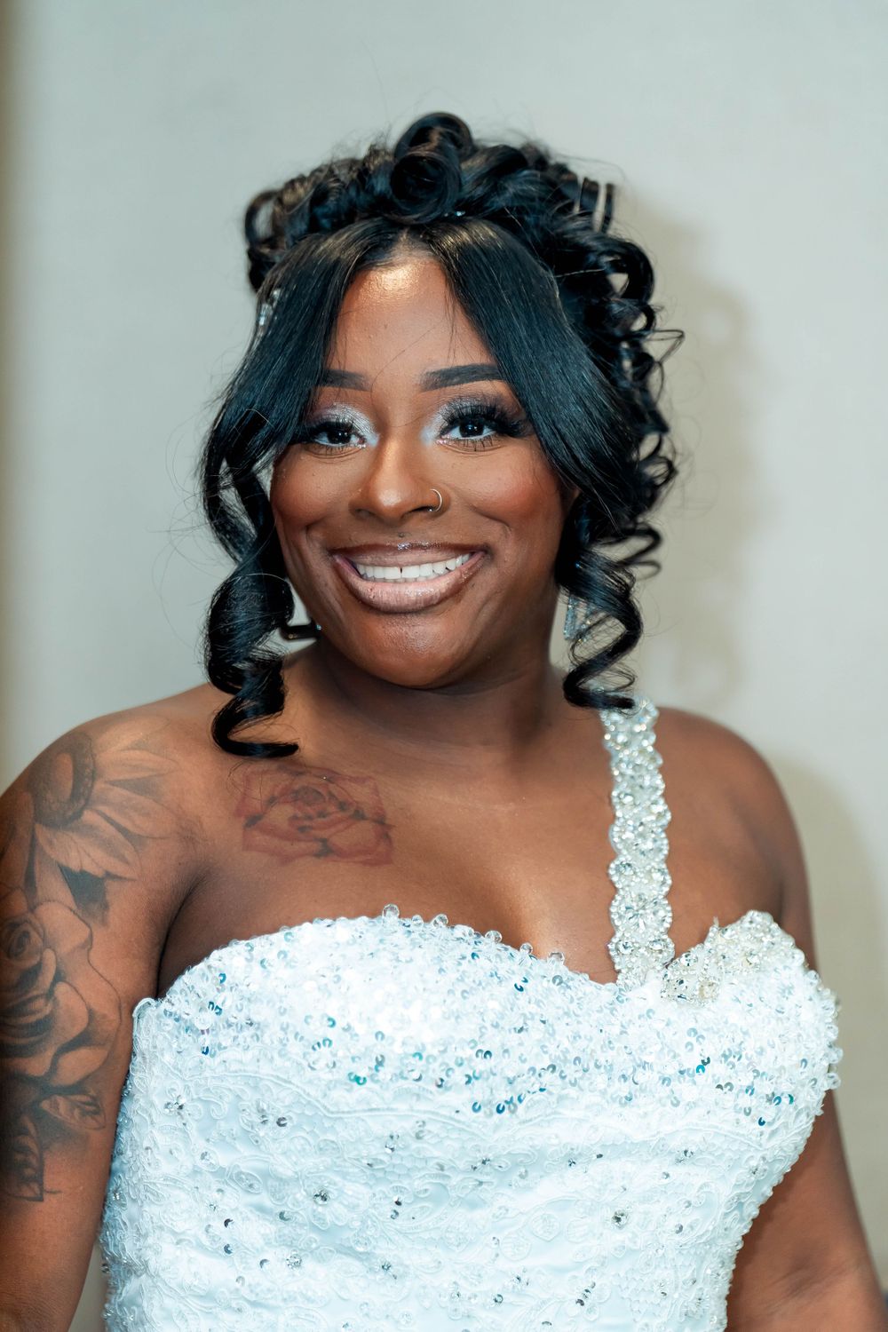 A bride wearing a sparkly white wedding dress shows her beautiful smile and styled curls.