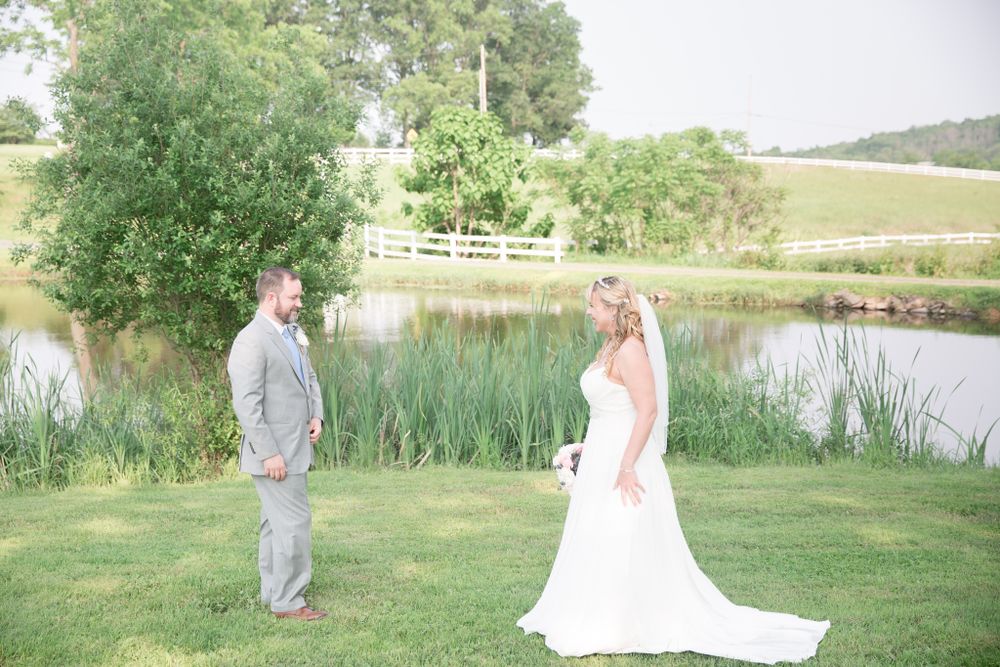 Elegant wedding portrait by a serene pond with lush greenery and cattails.