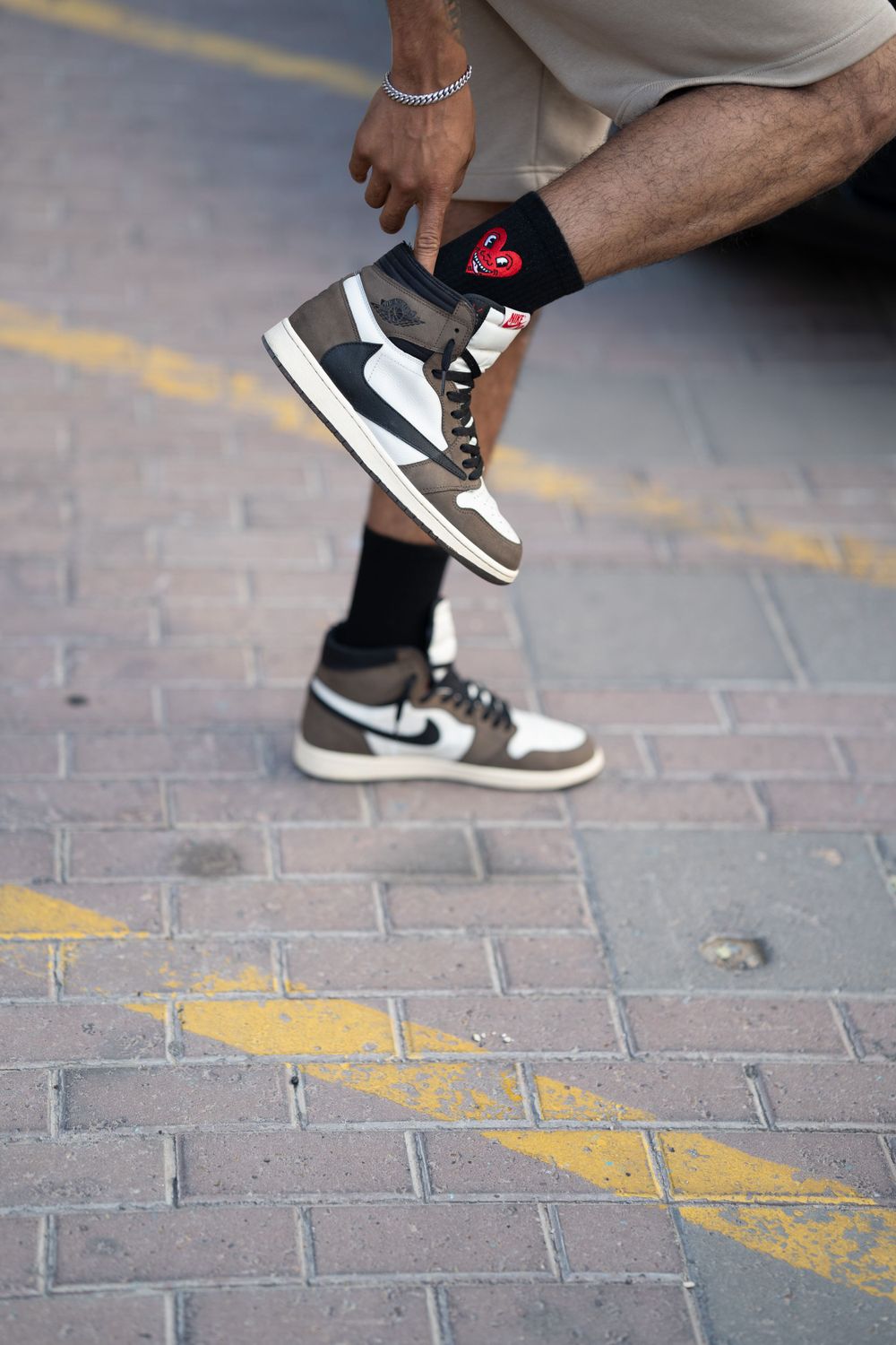 Close-up of black and white Nike sneaker with red heart sock detail on brick pavement.