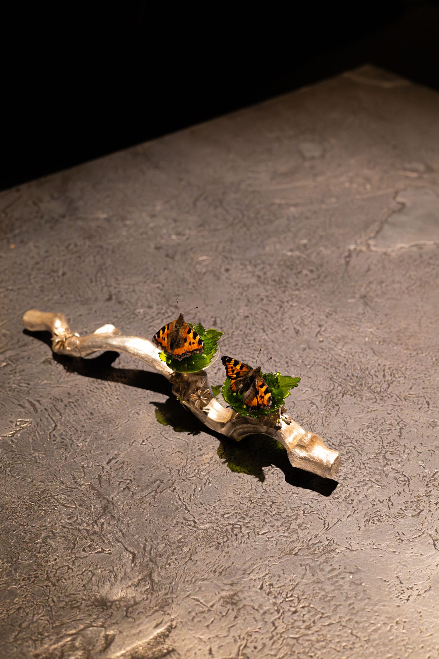 Artistic plating of garnished food on a curved driftwood piece against a textured gray surface.