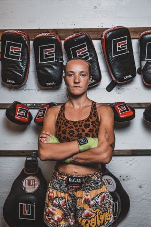 Fighter in leopard print gear posing confidently against wall of boxing equipment.