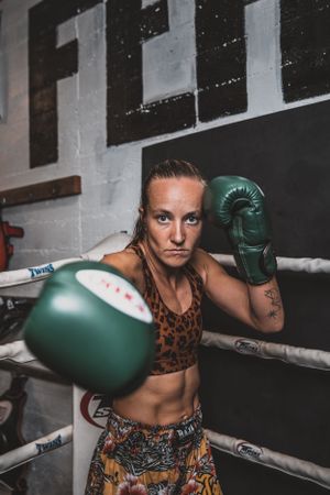 Boxer in animal print gear throwing punches with green gloves in training environment.