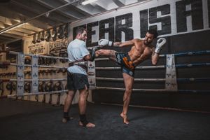 Kickboxers practicing fighting techniques in professional gym with dark walls.
