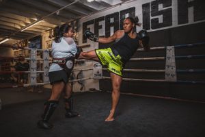 Training partners practicing kickboxing combinations in dark gym environment.