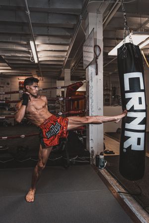 Martial artist demonstrates high kick technique in indoor training facility.