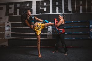 Two fighters practicing kickboxing techniques and sparring in professional gym setting.
