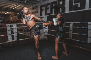 Martial artist executing powerful high kick during training session in boxing gym.