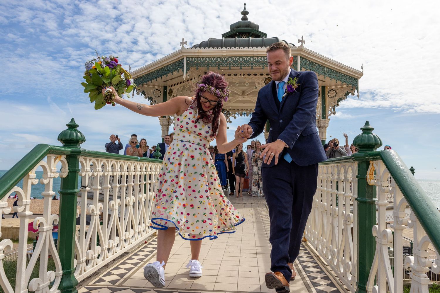 Couple dancing off the bandstand in Brighton just married with friends cheering in the background