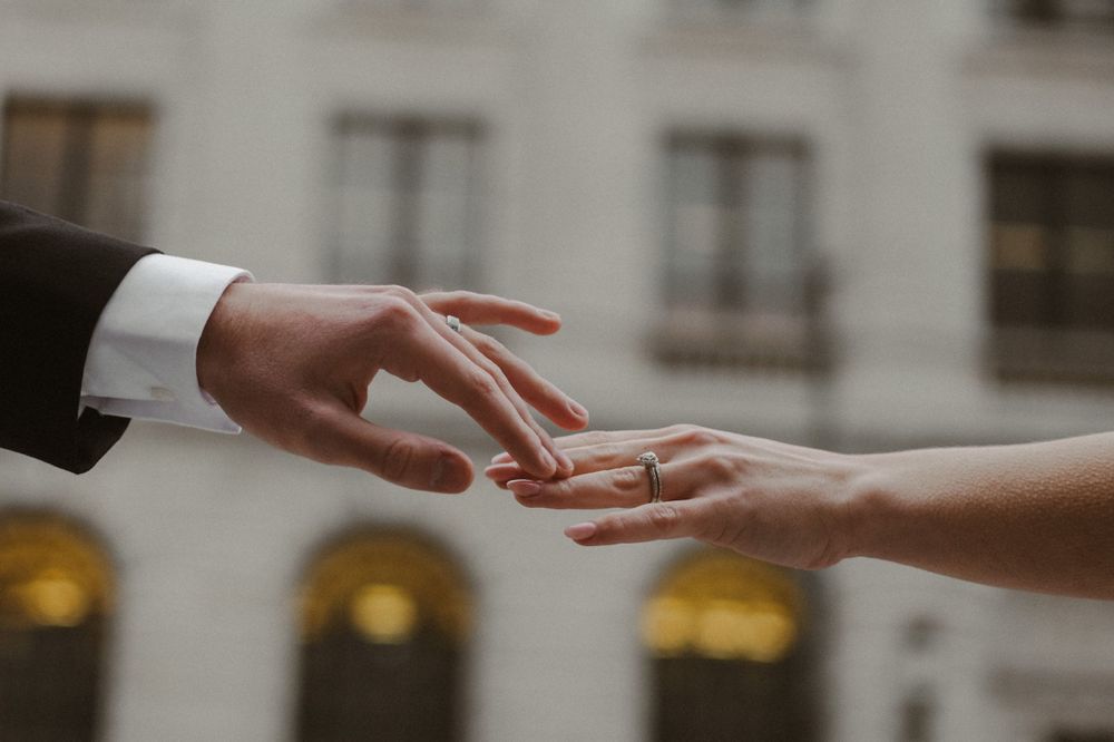 Close-up of hands exchanging wedding rings during ceremony.