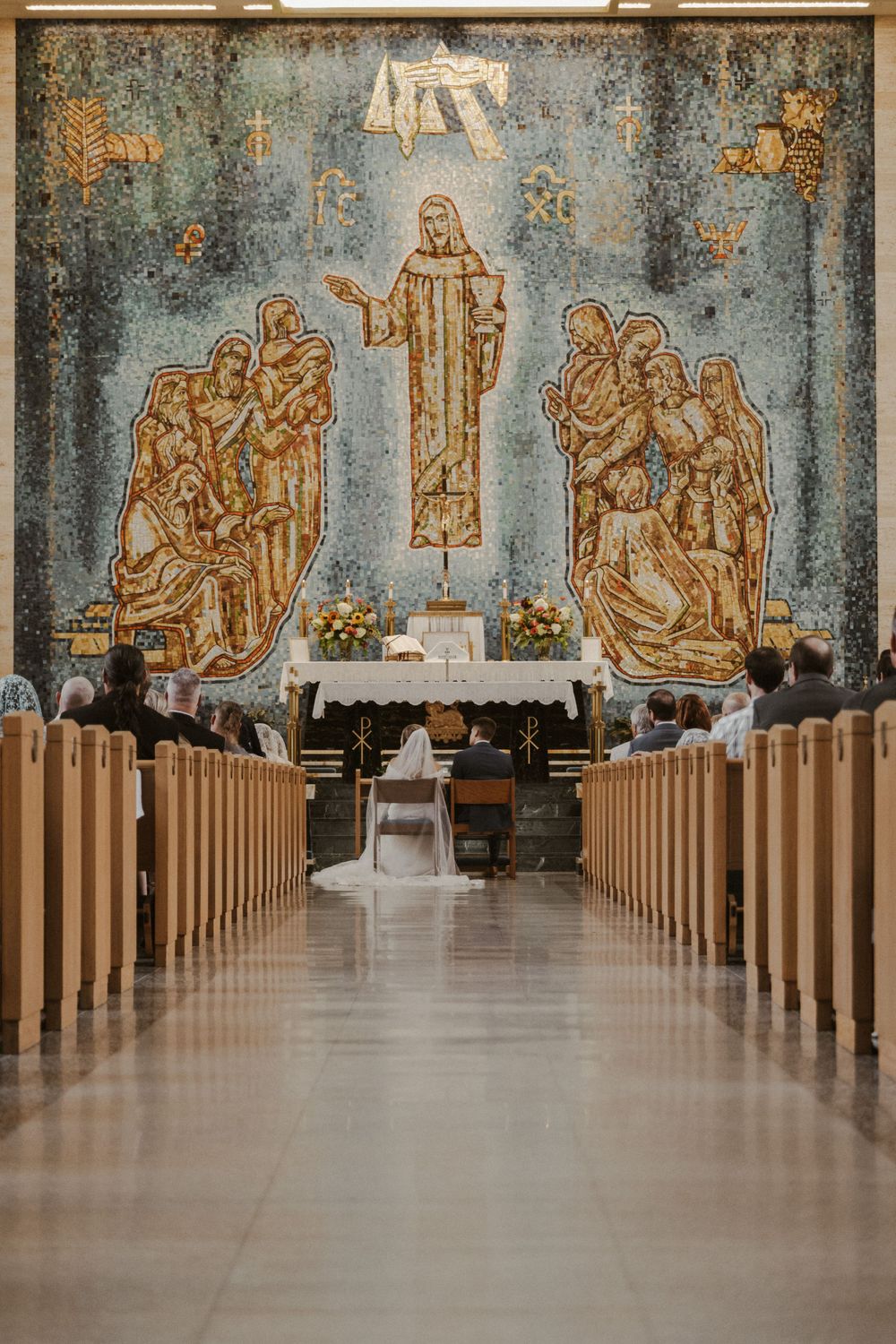 Church interior with wooden pews and religious murals along the walls.