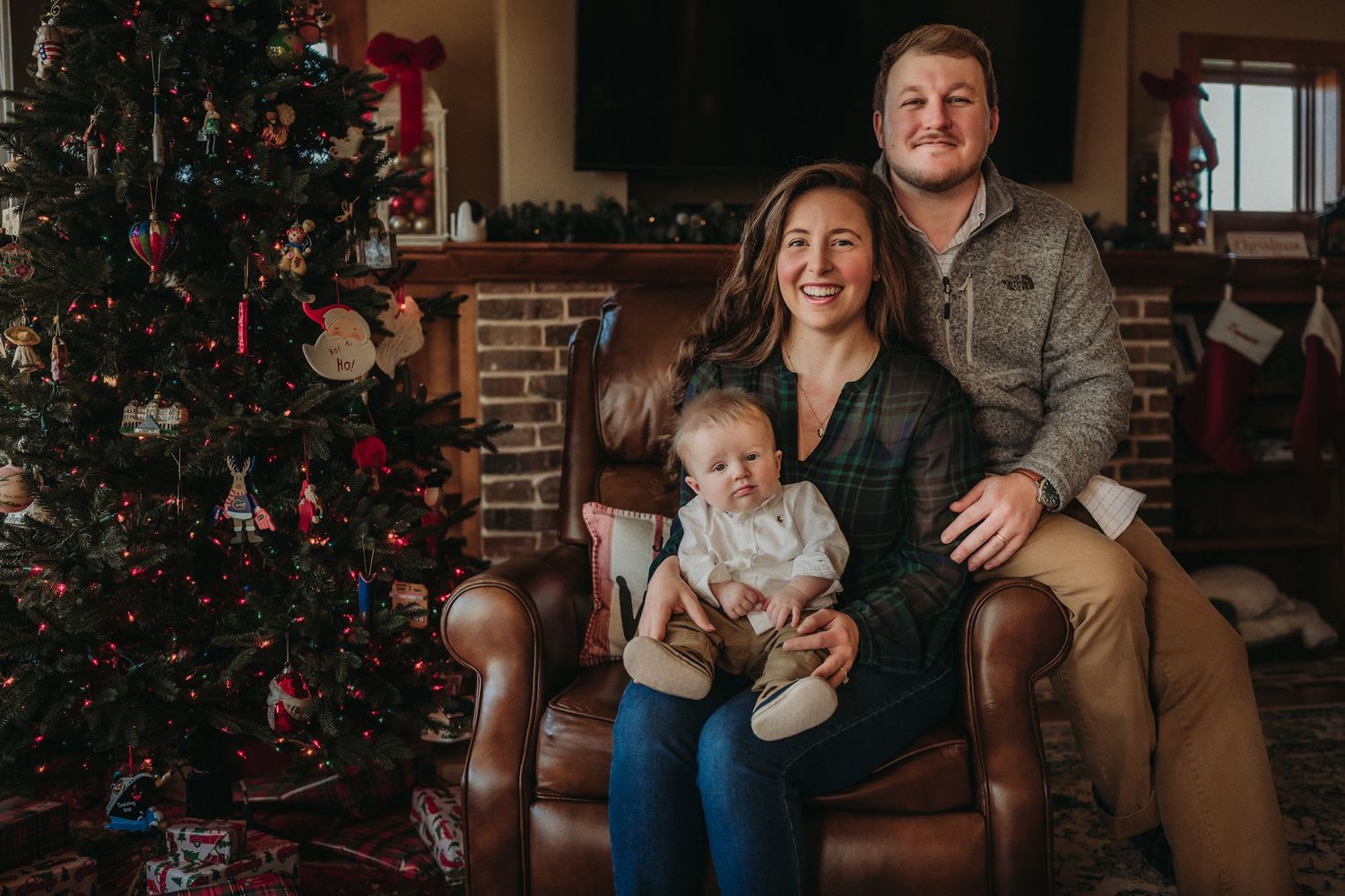 Festive family portrait by Christmas tree in cozy living room setting.
