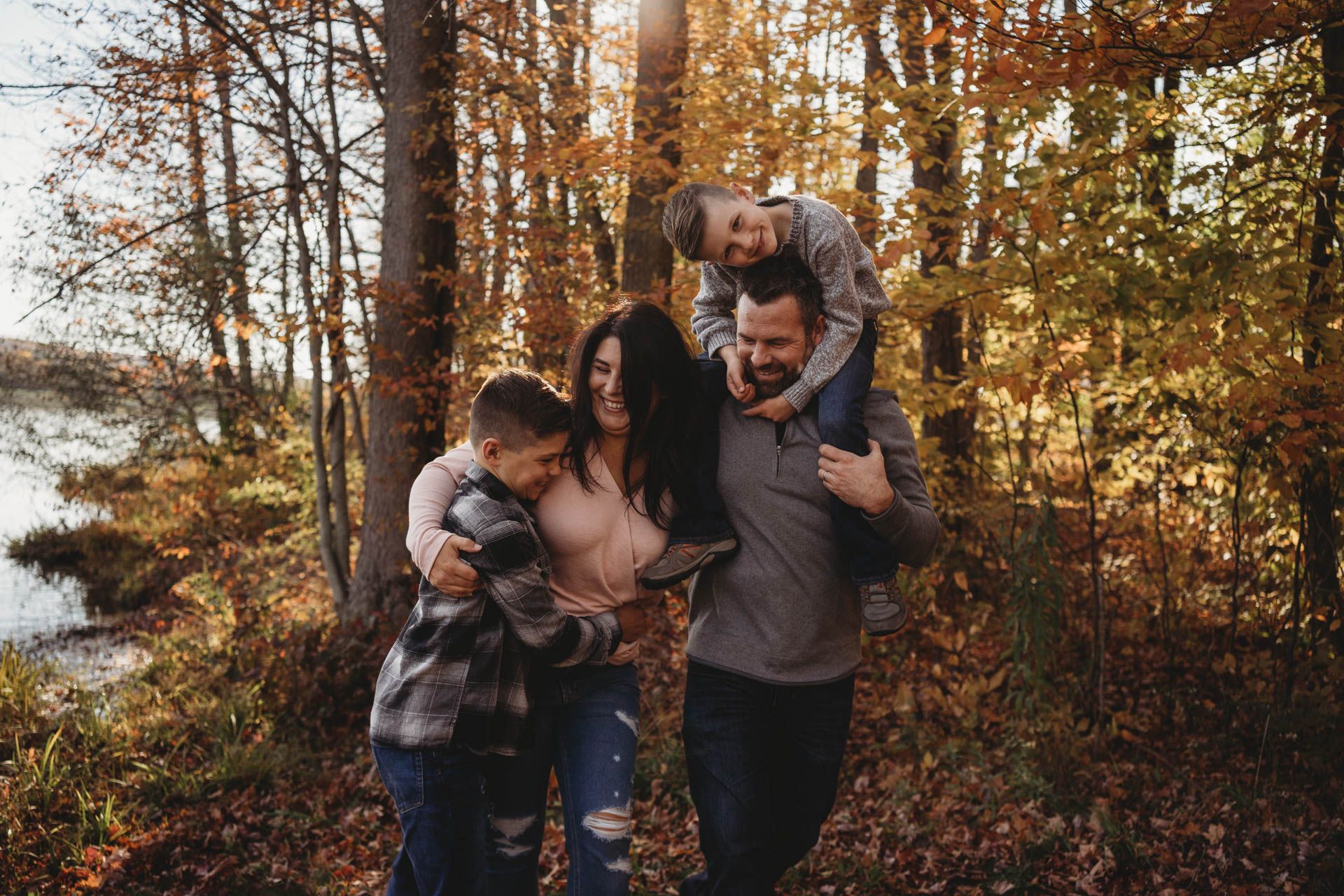 Family playing and having fun on autumn walk through sunlit forest.
