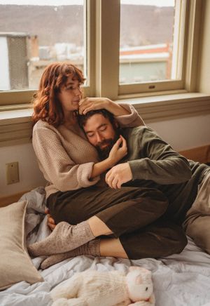 Couple sharing peaceful moment together by window in cozy bedroom setting.