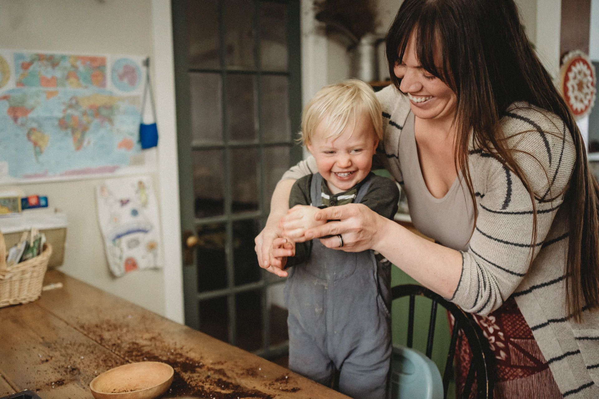 Parent and child sharing moment while looking at something together at wooden table.
