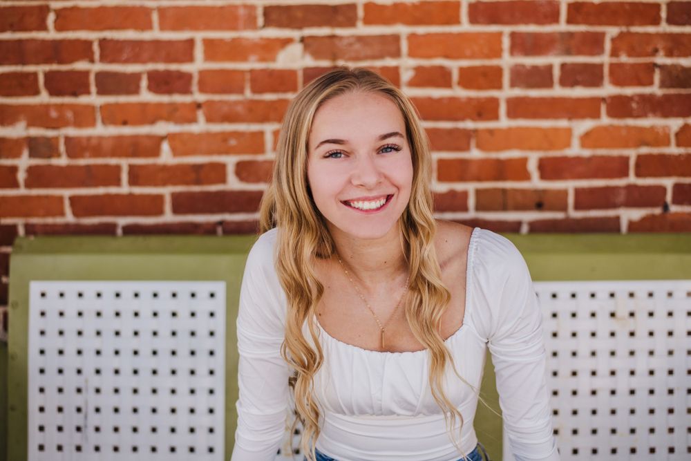 Casual portrait against red brick wall with white lattice seating.
