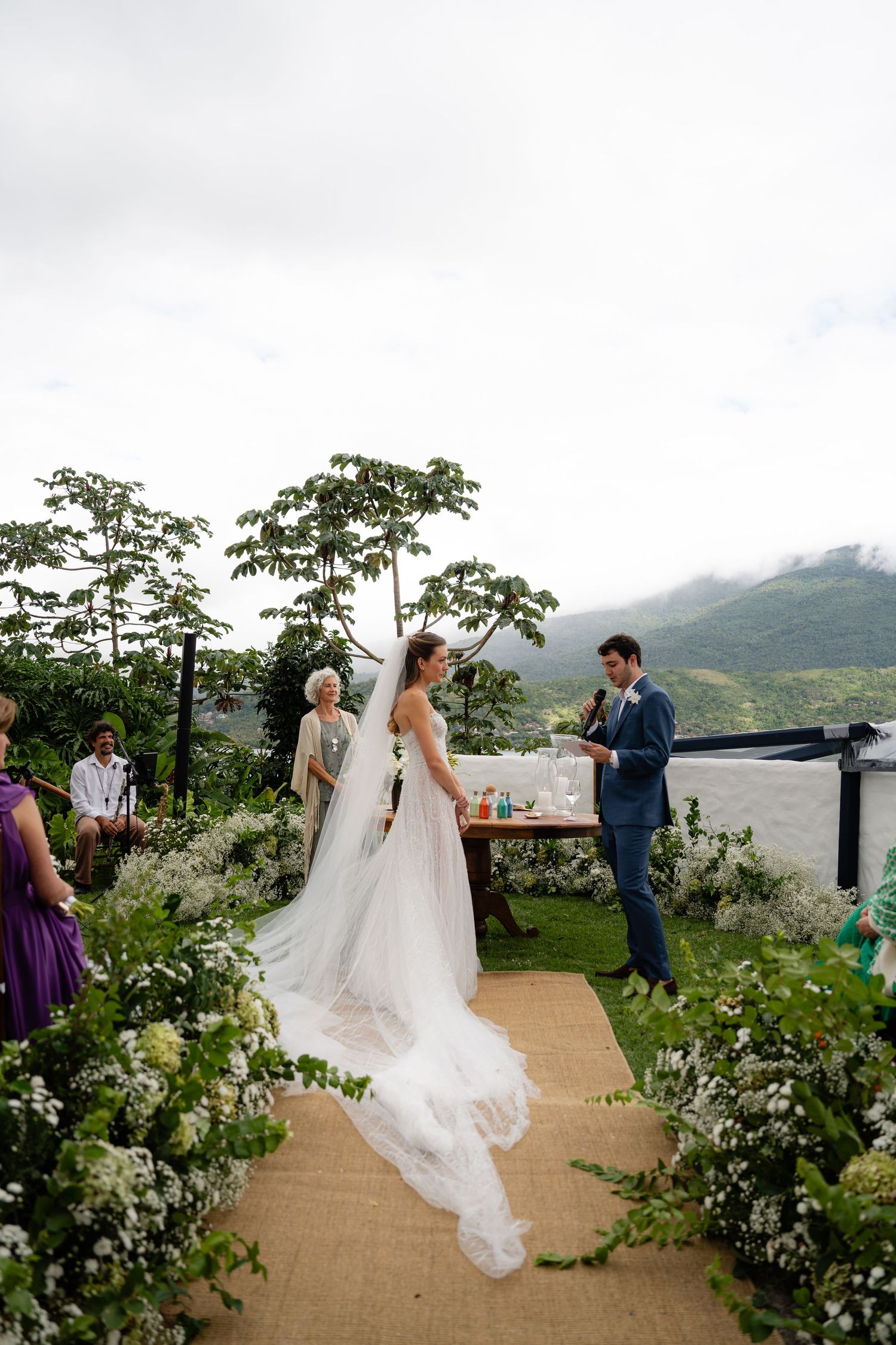 Outdoor wedding ceremony on a scenic mountain path decorated with white flowers.