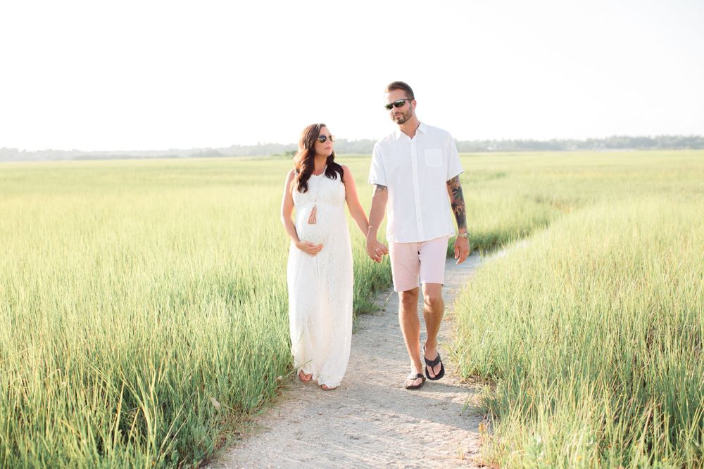 Romantic couple strolling together on a dirt path surrounded by green summer grass.