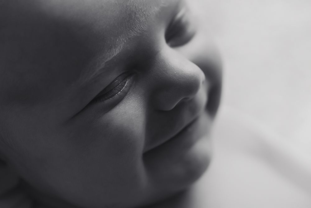 Close up macro shot of smiling newborn in black and white