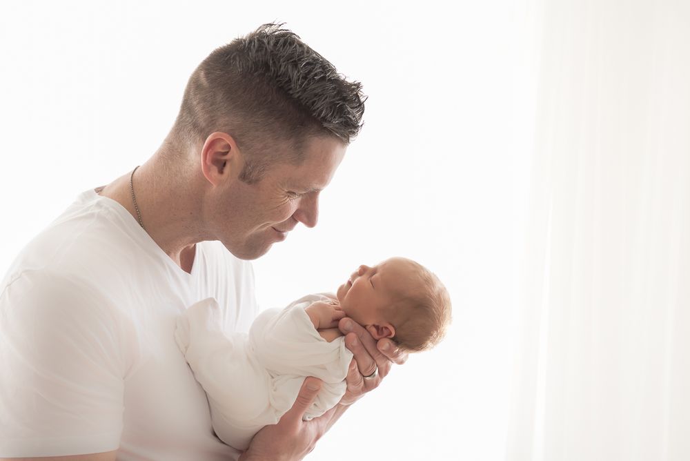 Dad poses with newborn son in beautifully profile backlit photo