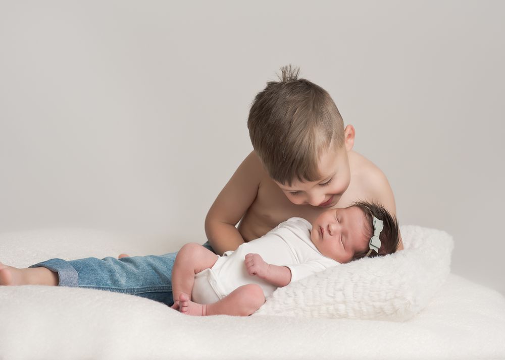 Big brother gives kisses to his newborn sister