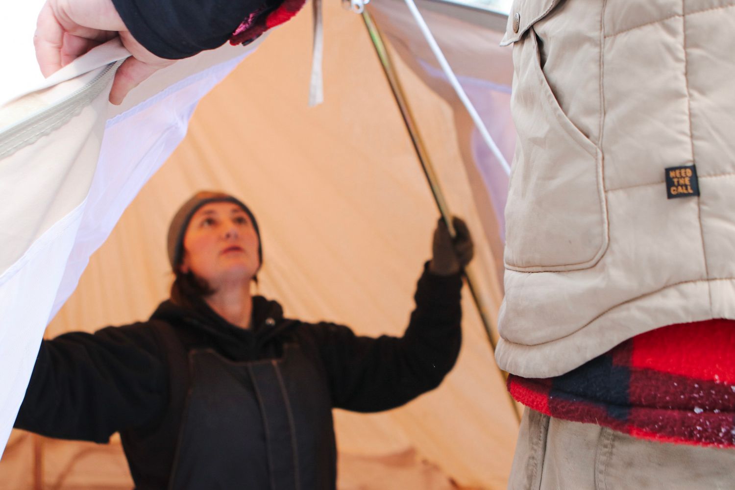 Setting up tent poles and structure during winter camping expedition.