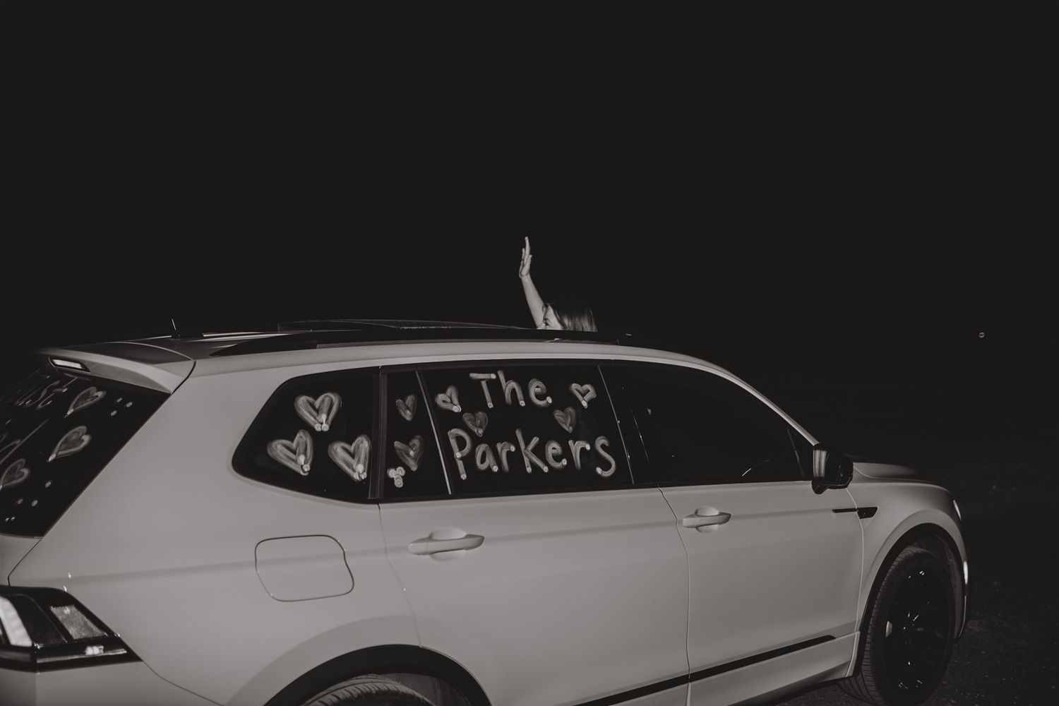 Black and white photo of decorated getaway car with writing on windows.